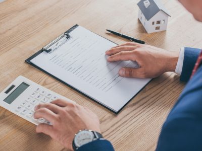 cropped view of businessman reading property management agreement and using calculator