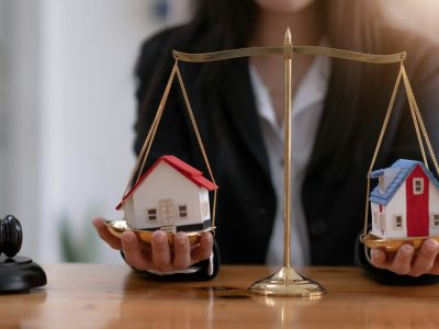 Female lawyer protecting a house model on a scales of justice. Property and legal concept. Houses